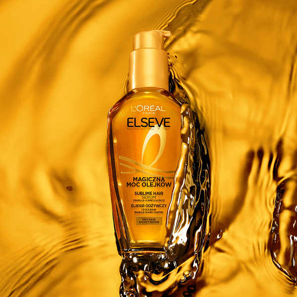 Butelka olejku Elseve Magiczna Moc Olejków od L’Oréal Paris umieszczona na lśniącej, wodnej powierzchni.