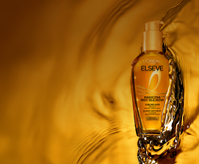 Butelka olejku Elseve Magiczna Moc Olejków od L’Oréal Paris umieszczona na lśniącej, wodnej powierzchni.